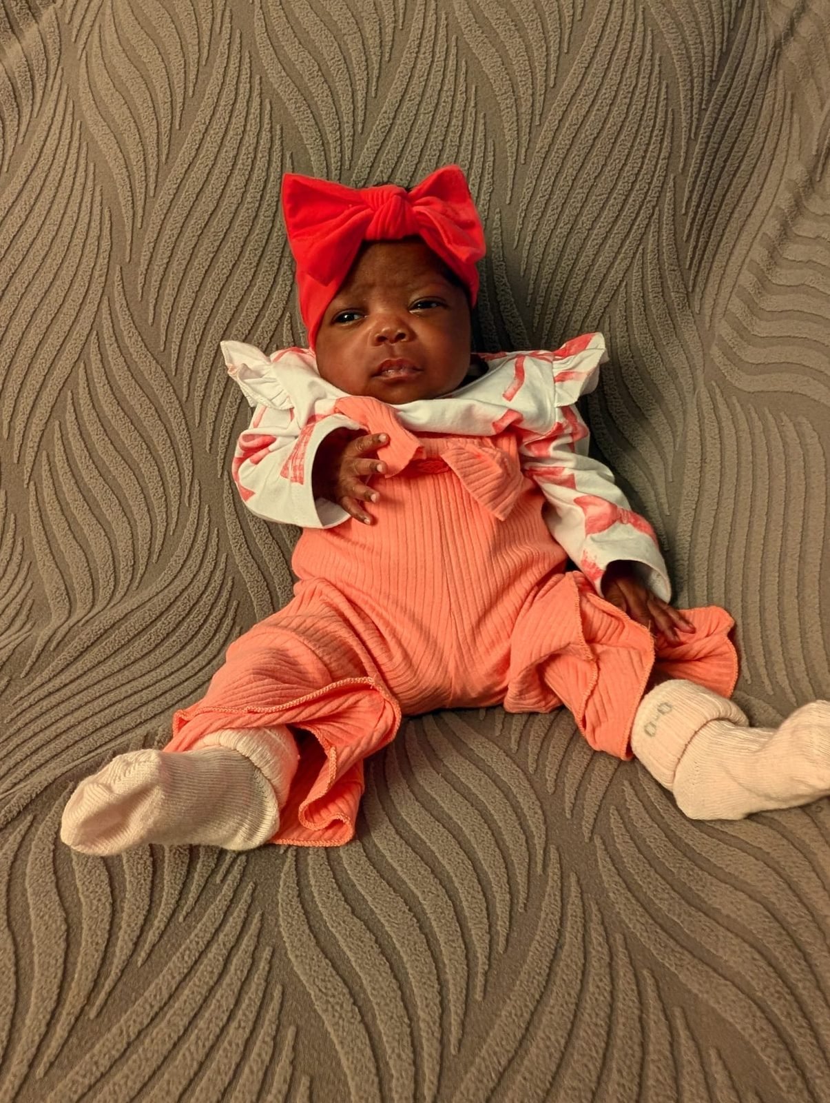 One of the Jakis triplets in a red bow headband
